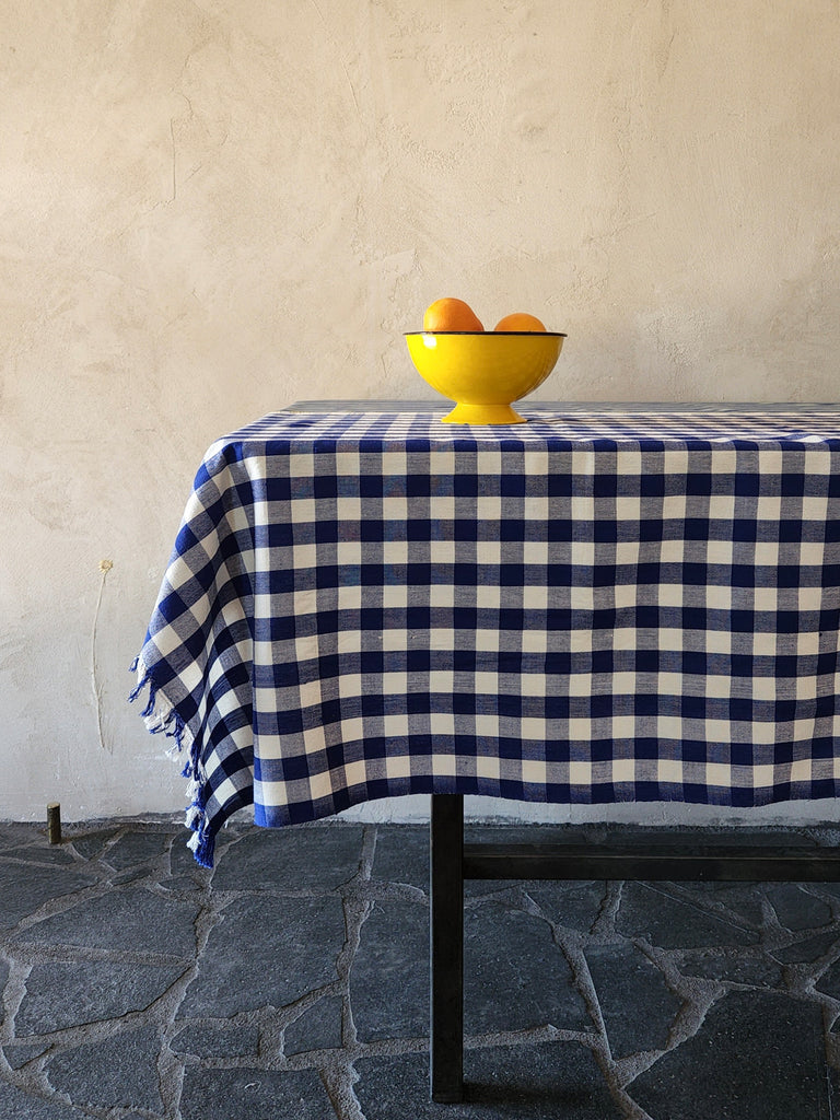 Blue gingham tablecloth with yellow bowl on it. 