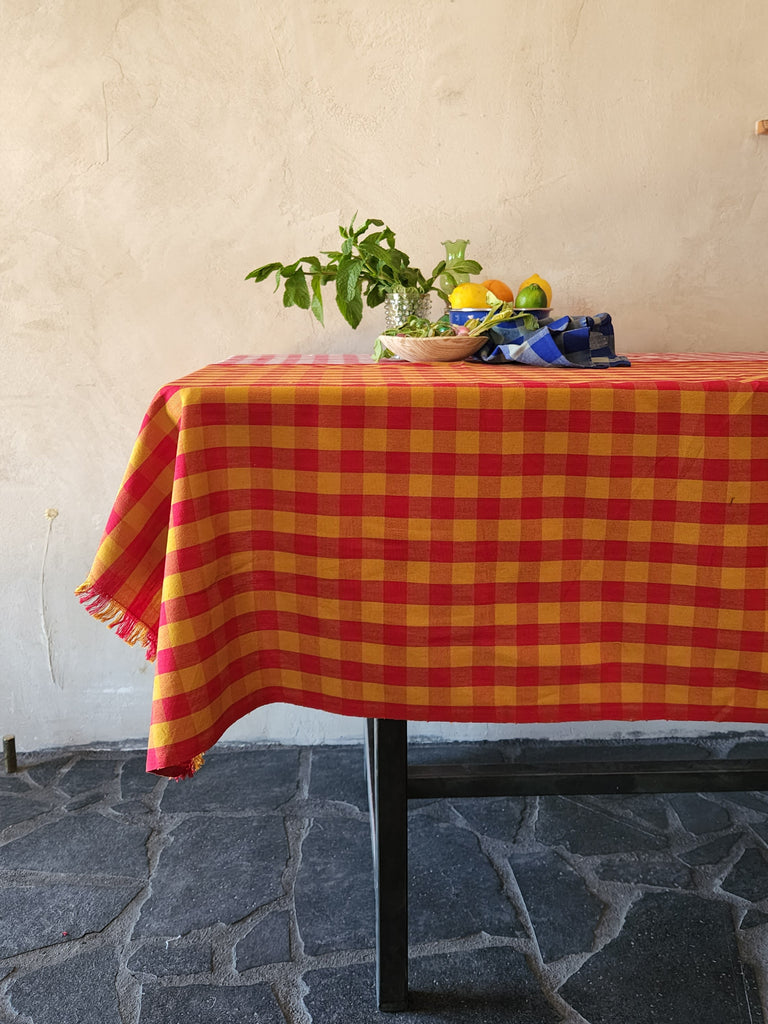 red and ochre gingham tablecloth with still life on top.