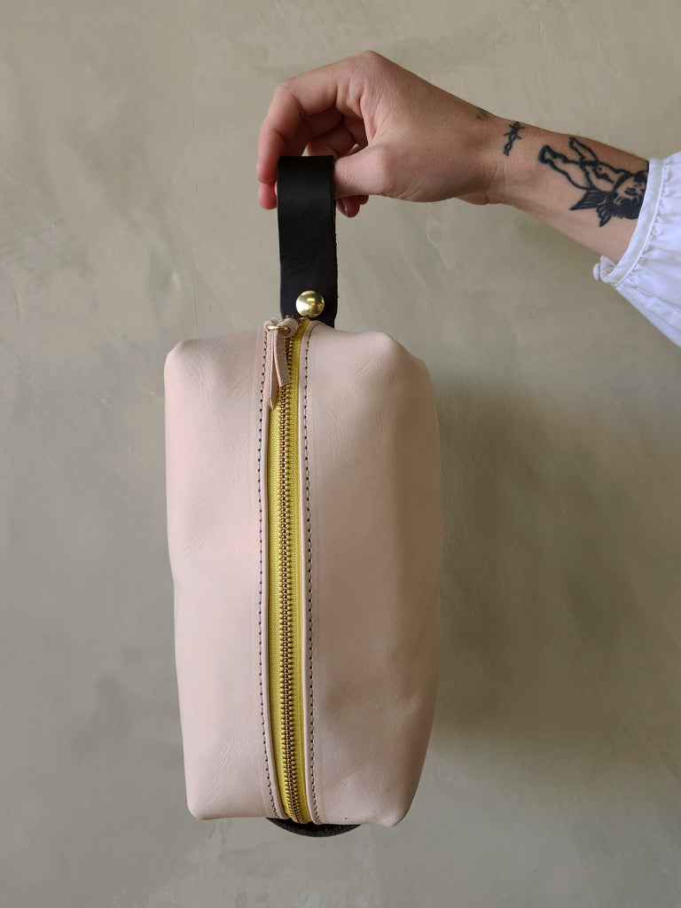 raw leather dopp toiletry kit with black strap.